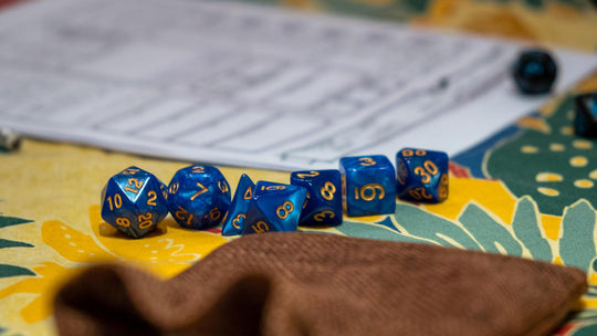 DND dice and character sheets on a colorful table. Image by Gian-Luca Riner on Unsplash. 