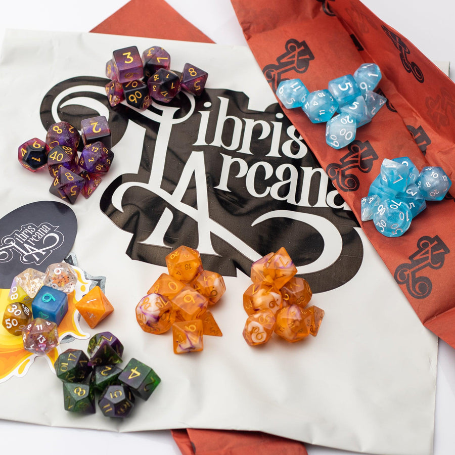Libris Arcana Dice Addict Subscription, 7 full sets of dice, 7 random dice, and packaging laid out on a white background.