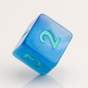 Infinite, cloudy blue dice with glittery inclusions and teal numbering. D6 on white background.
