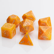 Orcana--Orange swirled RPG dice with gold metallic inking. 7 piece RPG dice set on white background.