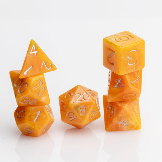 Orcana--Orange swirled RPG dice with gold metallic inking. 7 piece RPG dice set stacked on white background.