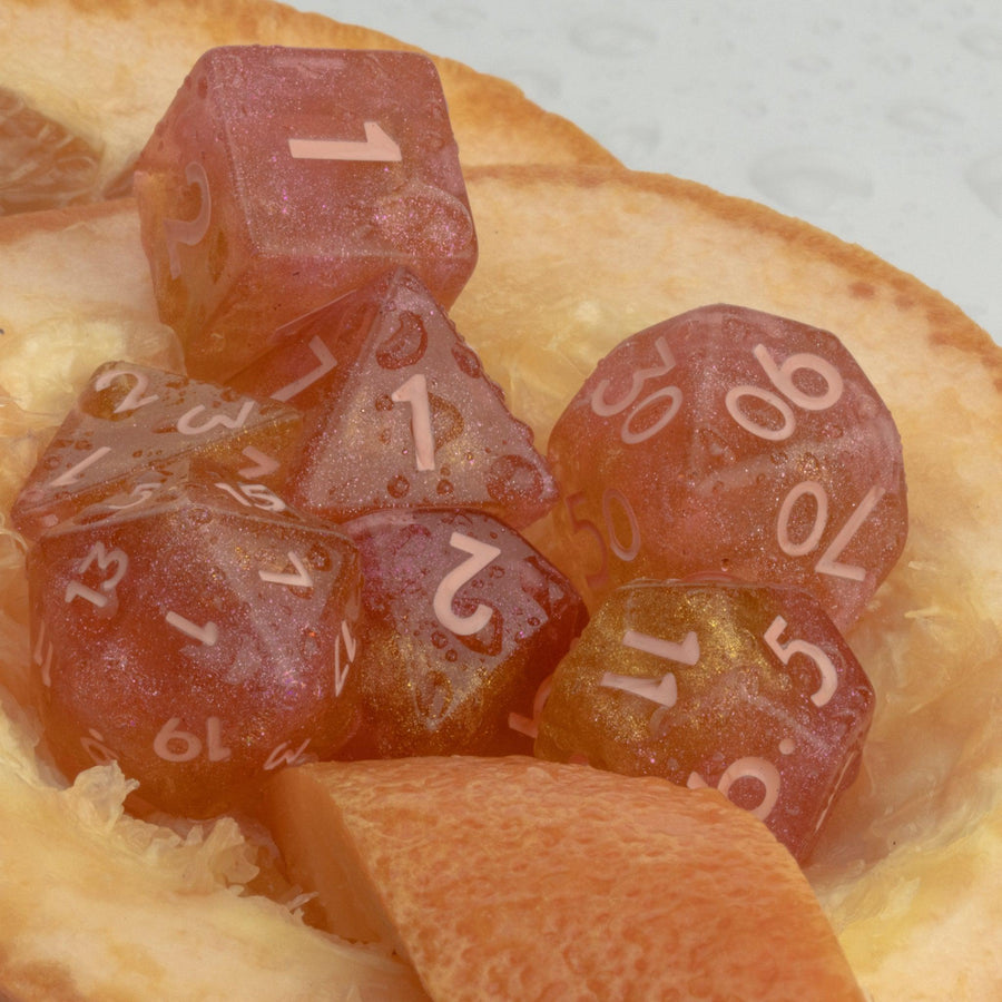 Pamplemousse, 7 piece RPG dice set lain on grapefruit rind.