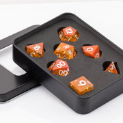Sunfire, swirling orange and red handmade DND dice set in decorative tin on a white background.